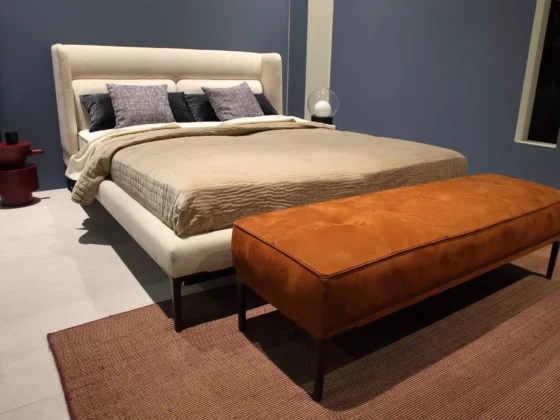 Beiges Wittmann Boxspringbett mit gepolstertem Kopfteil, braune Sitzbank am Fußende, modernes Schlafzimmer-Design