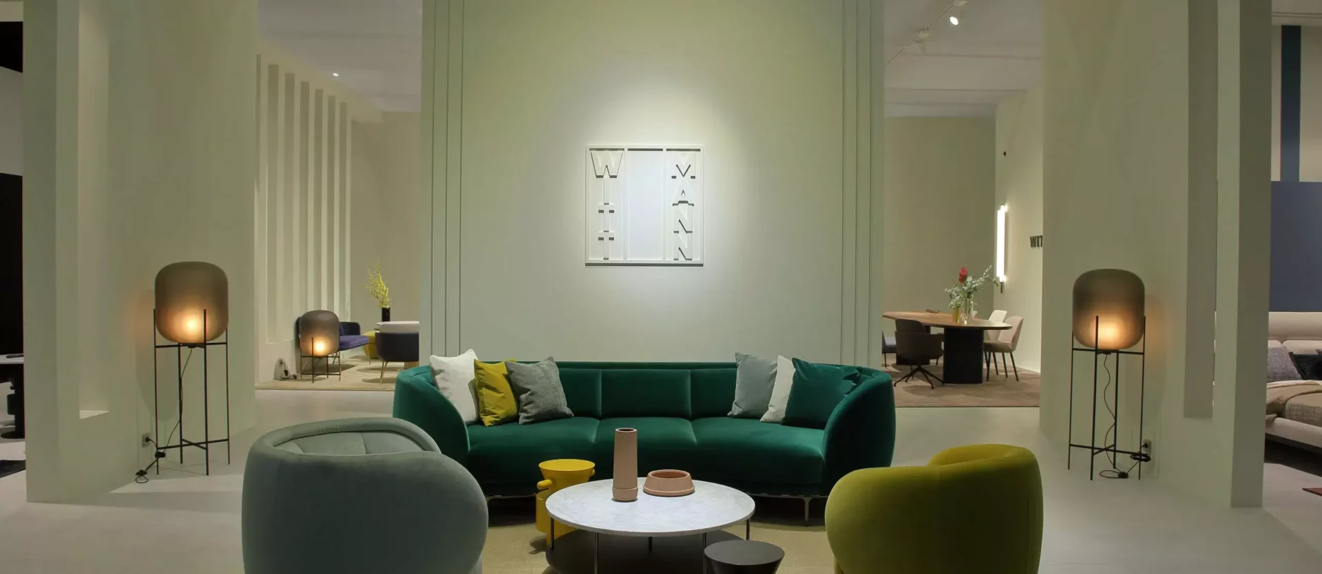 Moderner Showroom mit Wittmann Designermöbeln, grünem Sofa, zwei Sesseln, runden Tischen und stimmungsvoller Beleuchtung in