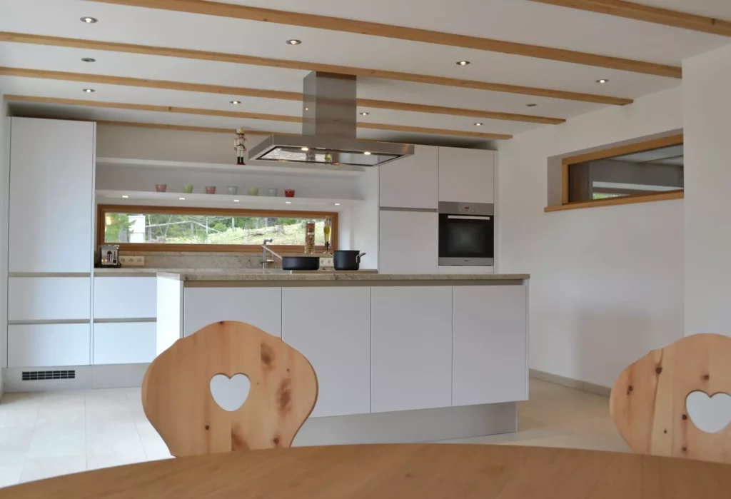 Moderne weiße Küche mit Kochinsel, Holzstühlen mit Herz-Ausschnitt und Fensterfront, Ferienhaus Wagrain, Referenzen