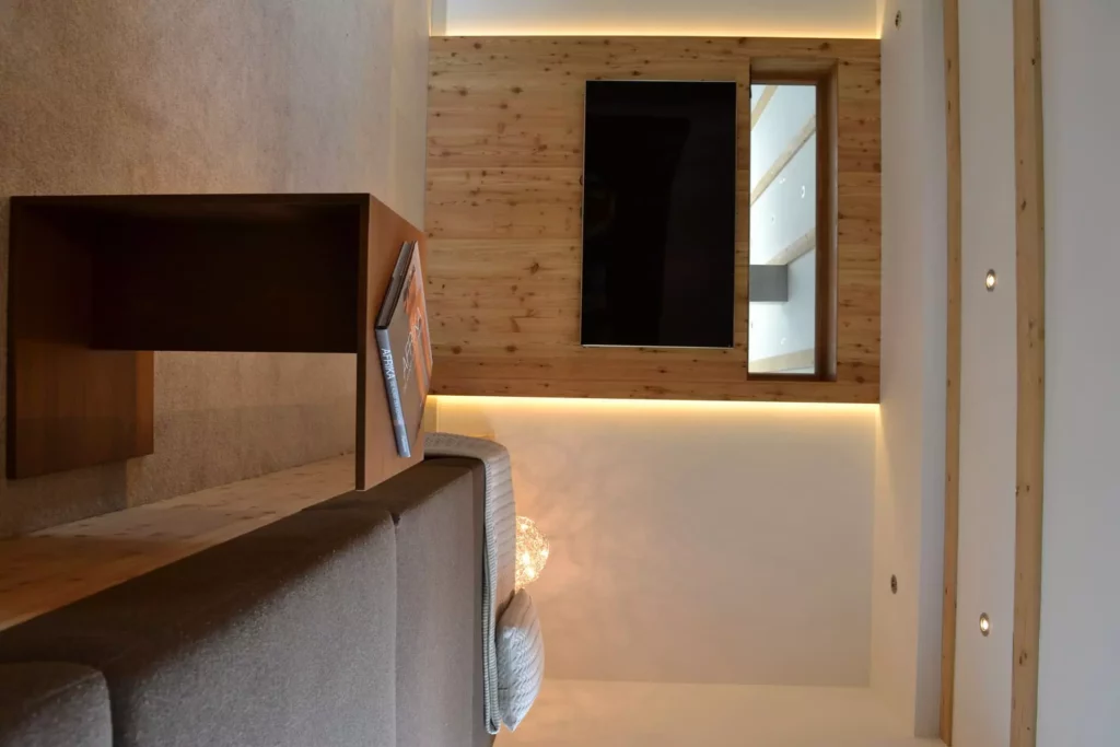 Moderner Wohnraum mit maßgefertigter Holzwand, integriertem Fernseher, Sofa und Beistelltisch im Ferienhaus, Referenzen