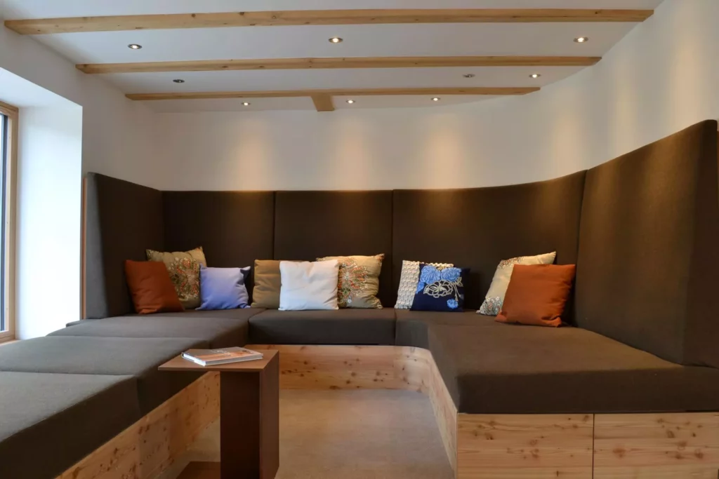 Maßgefertigte Eckbank aus Holz mit braunen Polstern und bunten Kissen in modernem Ferienhaus in Wagrain, Referenzen