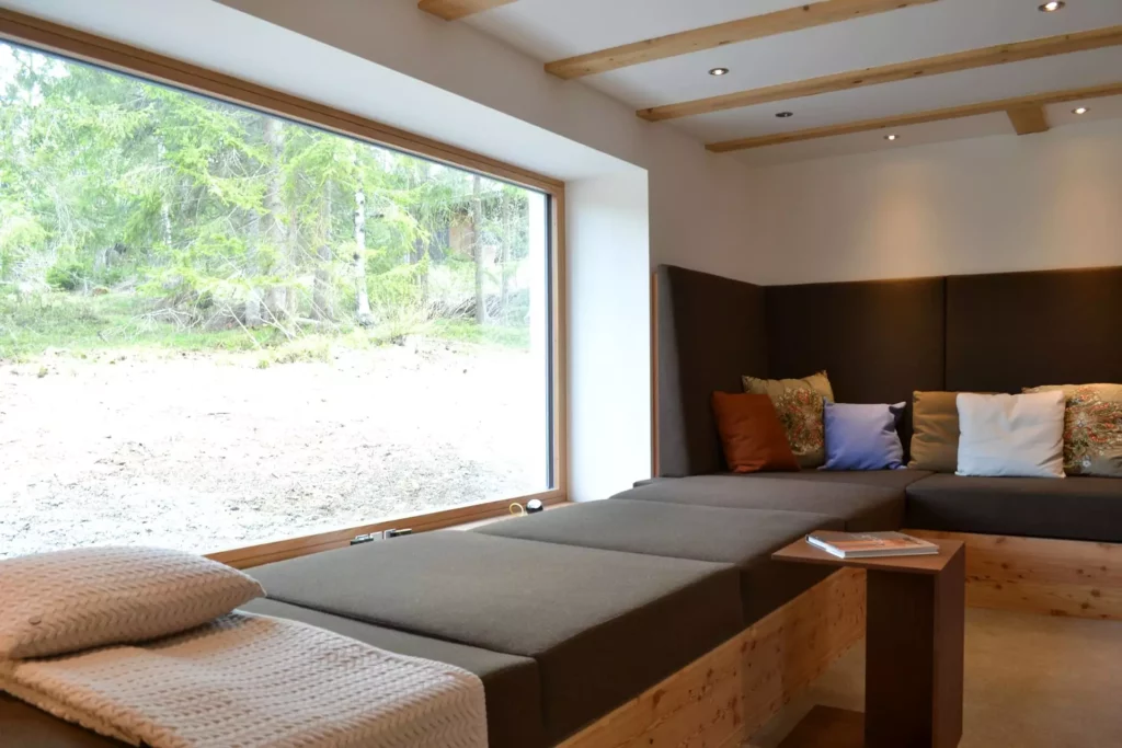 Modernes Ferienhaus-Wohnzimmer mit maßgefertigter Polsterecke aus Holz, großen Fenstern und dekorativen Kissen, Referenzen