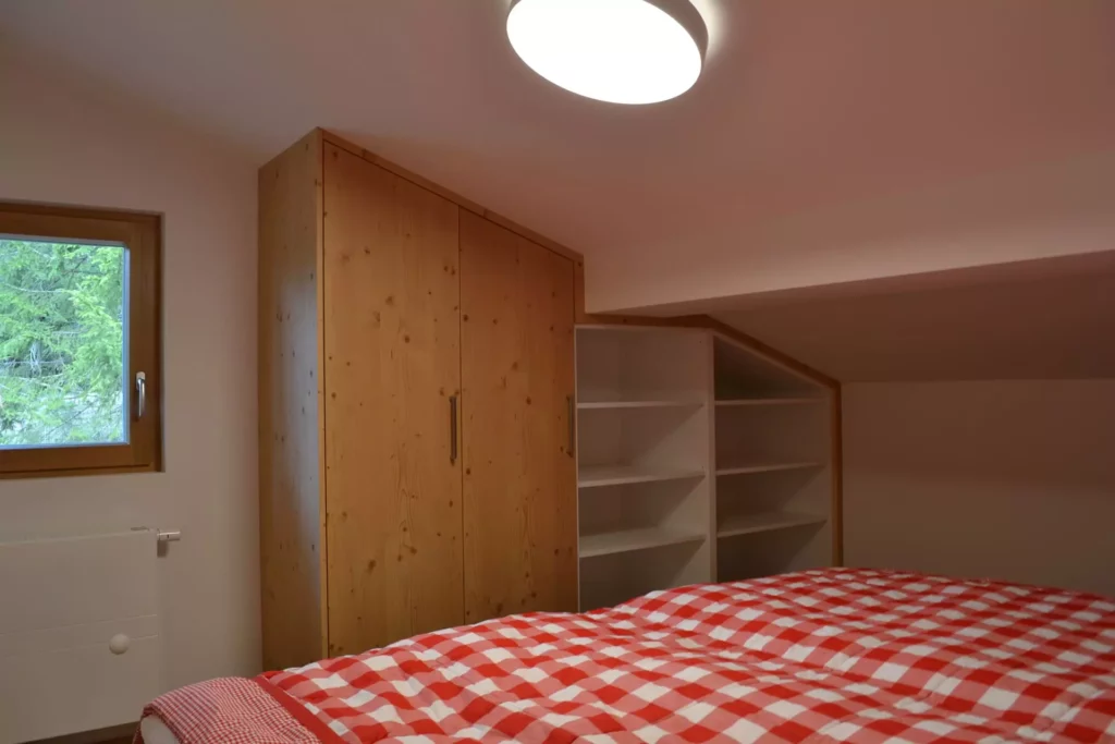 Schlafzimmer mit maßgefertigtem Holzschrank und offenen weißen Regalen unter Dachschräge, rotes kariertes, Referenzen