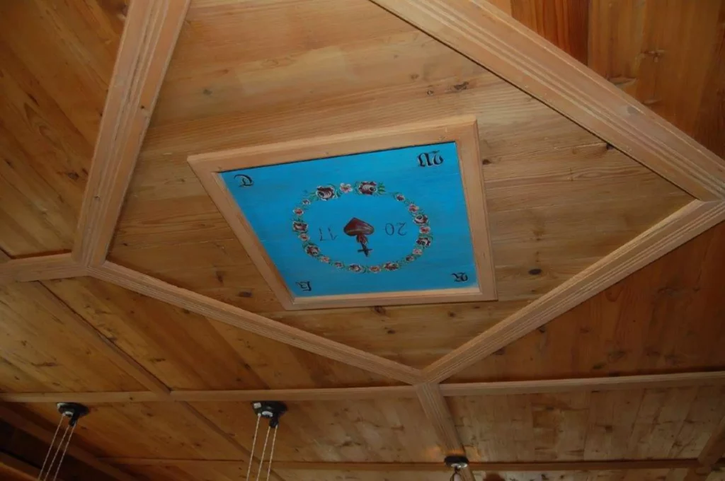 Holzdecke mit quadratischem Rahmen und blauem Feld in der Mitte, bemalt mit Blumenkranz und Spielkartensymbol Pik, Referenzen
