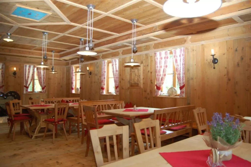 Rustikaler Gastraum mit maßgefertigten Holzmöbeln, roten Sitzpolstern, Holzvertäfelung und dekorativen Vorhängen, Referenzen