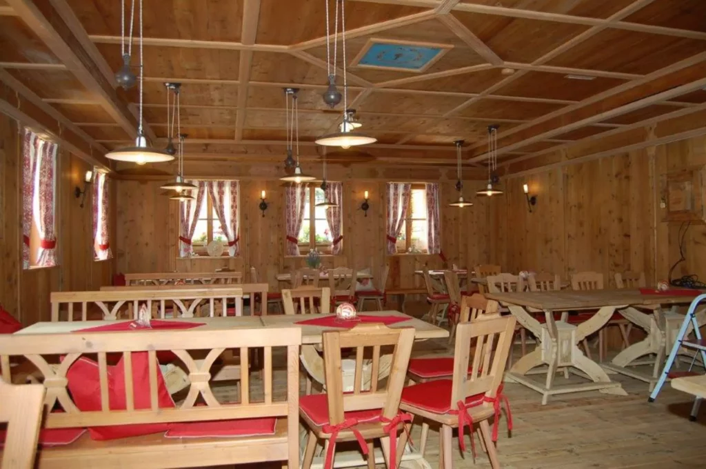 Rustikale Gaststube mit maßgefertigten Holzmöbeln, roten Sitzkissen und traditioneller Innenarchitektur in, Referenzen