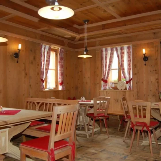 Rustikaler Gastraum mit maßgefertigten Holztischen und Stühlen mit roten Sitzkissen, Holzvertäfelung und, Referenzen
