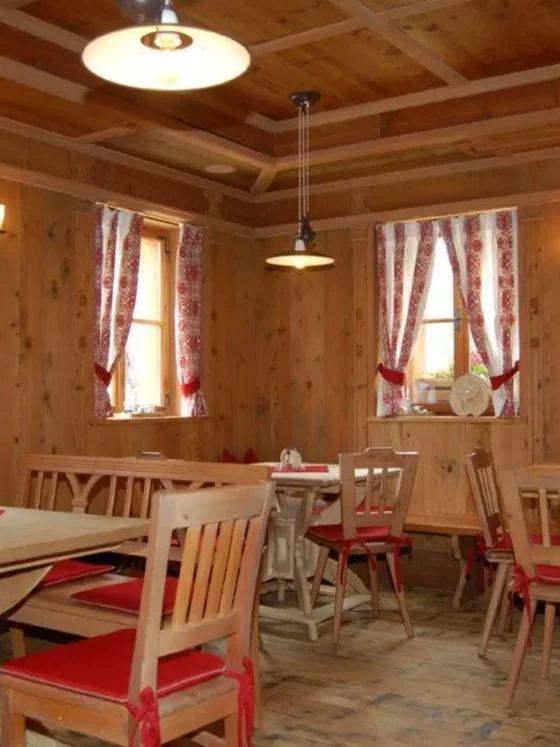 Rustikaler Gastraum mit maßgefertigten Holztischen und Stühlen mit roten Sitzkissen, Holzvertäfelung und, Referenzen