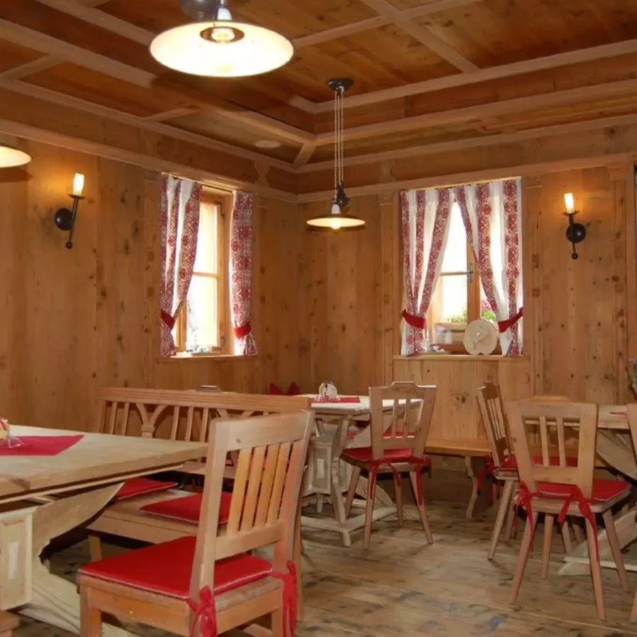 Rustikaler Gastraum mit maßgefertigten Holztischen und Stühlen mit roten Sitzkissen, Holzvertäfelung und, Referenzen