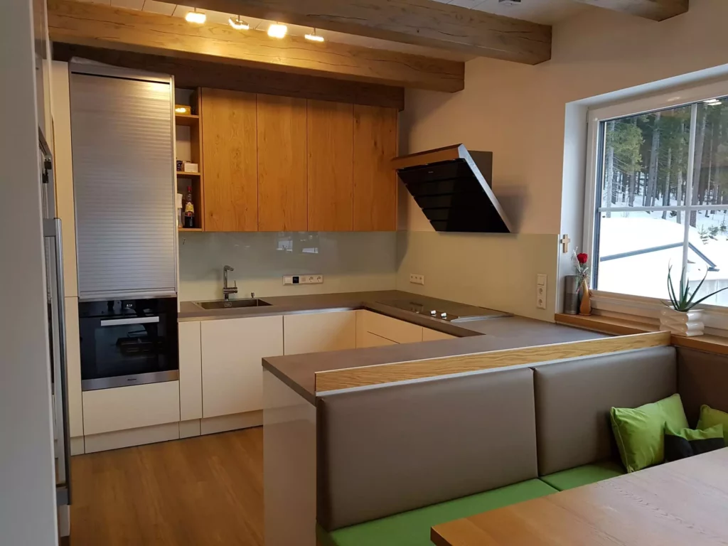 Moderne Küche mit maßgefertigten Holzfronten, integrierter Eckbank mit grünem Polster und großem Fenster mit, Referenzen