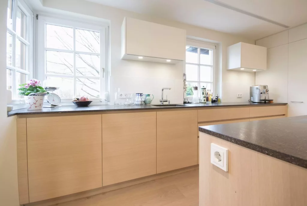 Moderne Poliform Küche mit hellen Holzfronten, schwarzer Arbeitsplatte, zwei Fenstern, weißen Hängeschränken und, Referenzen