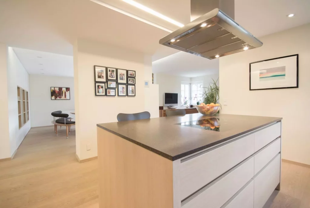 Moderne offene Küche mit Poliform Kochinsel, Dunstabzug, Essbereich und Wohnraum mit TV, helles Holz und, Referenzen