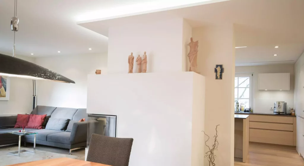 Offener Wohnraum mit moderner Poliform Küche, grauem Sofa mit roten Kissen, Kamin und skulpturaler Dekoration in, Referenzen