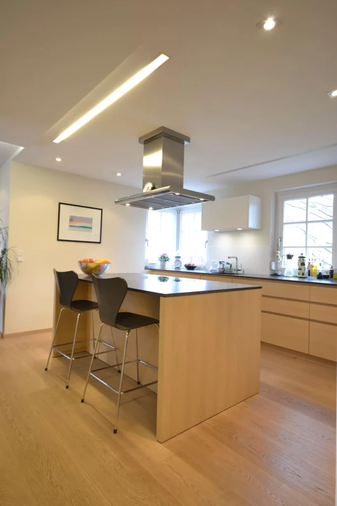 Moderne Poliform Küche in hellem Holz mit Kochinsel, schwarzen Barhockern und Edelstahl-Dunstabzug in offenem, Referenzen
