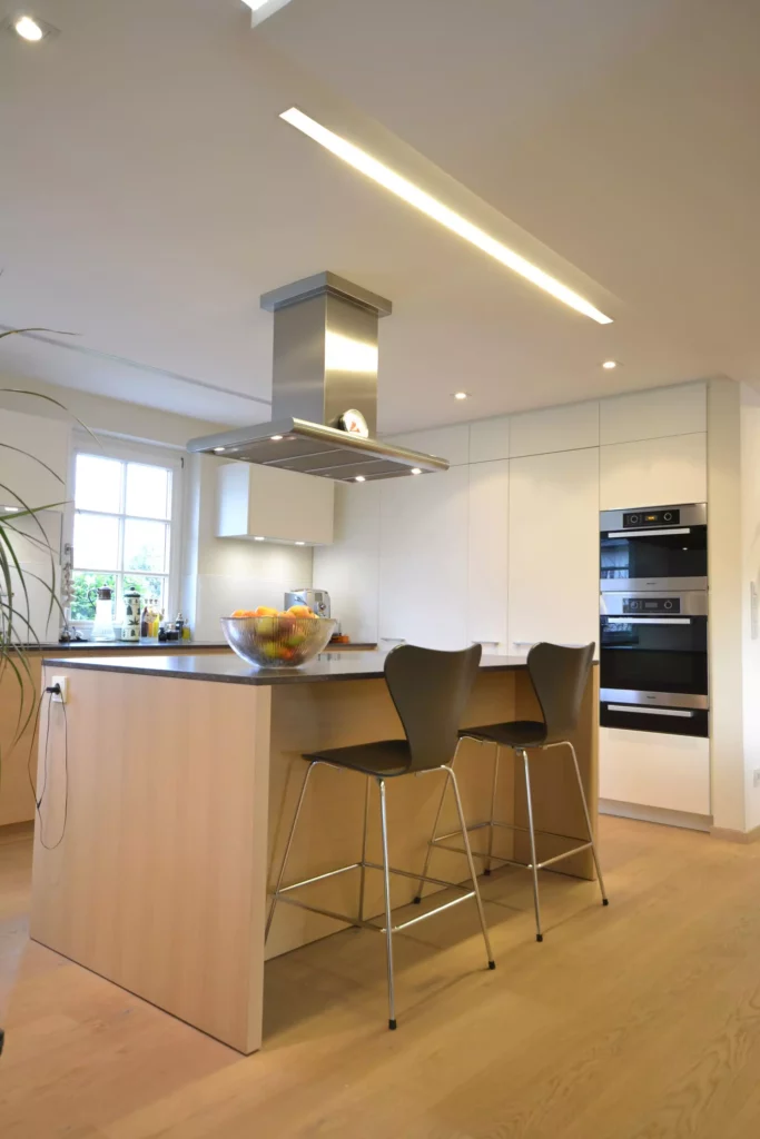 Moderne Poliform Küche in hellem Holz mit Kochinsel, Edelstahl-Dunstabzug und zwei schwarzen Barhockern in, Referenzen