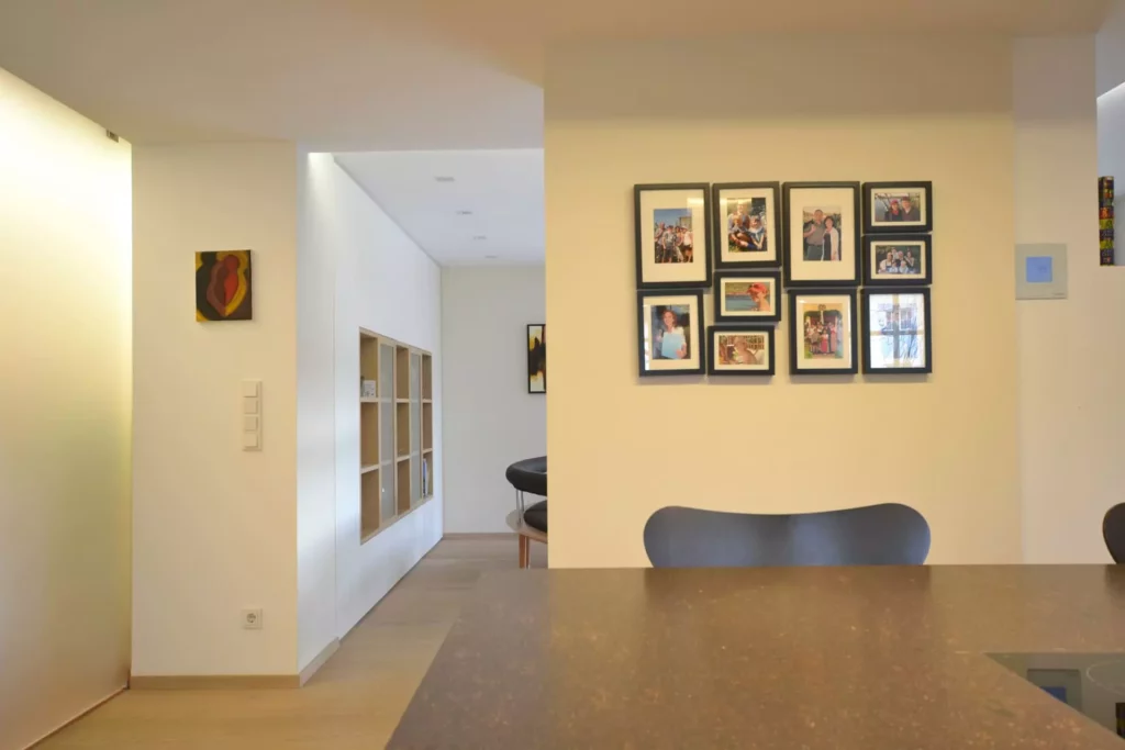 Moderner Wohnraum mit Poliform-Küche, Holzregal, Familienfotos an der Wand und minimalistischer Innenarchitektur, Referenzen