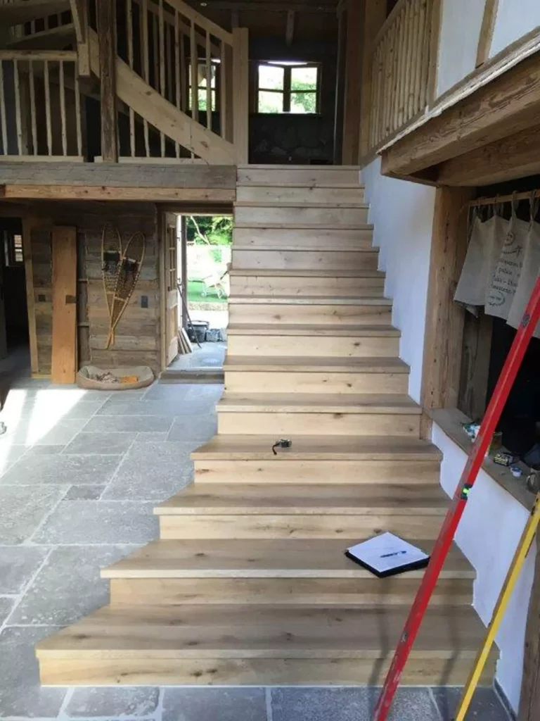 Holztreppe in rustikalem Innenraum mit Steinboden, sichtbaren Holzbalken und handwerklichen Werkzeugen im, Referenzen