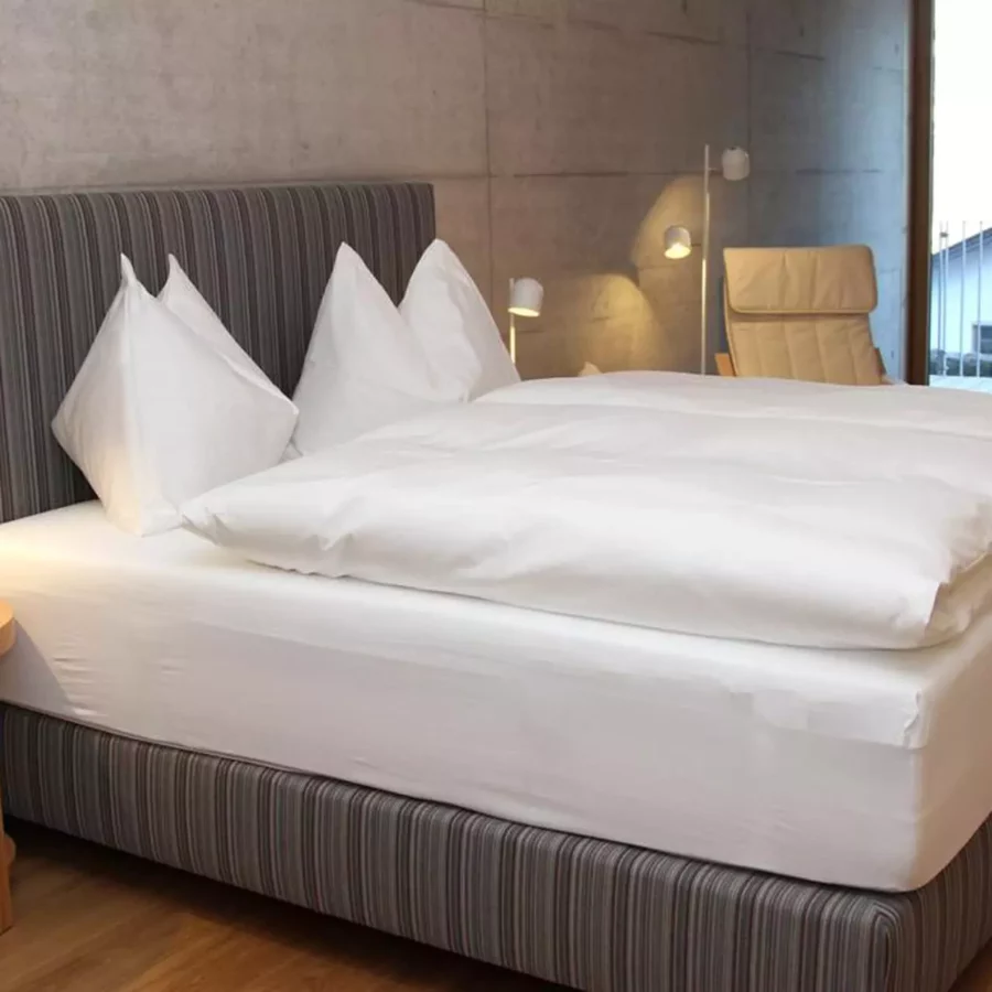 Modernes Schlafzimmer mit gestreiftem Polsterbett, weißer Bettwäsche, Holz-Nachttisch, Leselampen und beiger, Referenzen