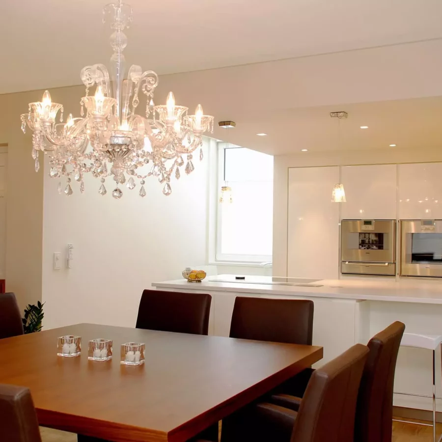 Moderner Essbereich mit braunem Holztisch, Lederstühlen, Kristall-Kronleuchter und offener weißer Küche mit, Referenzen