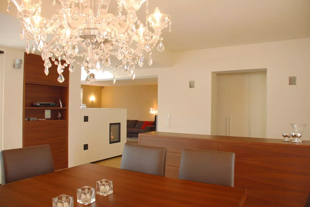 Moderner Essbereich mit maßgefertigten Holzmöbeln, Lederstühlen, Kamin und elegantem Kristallleuchter in Wohnung, Referenzen