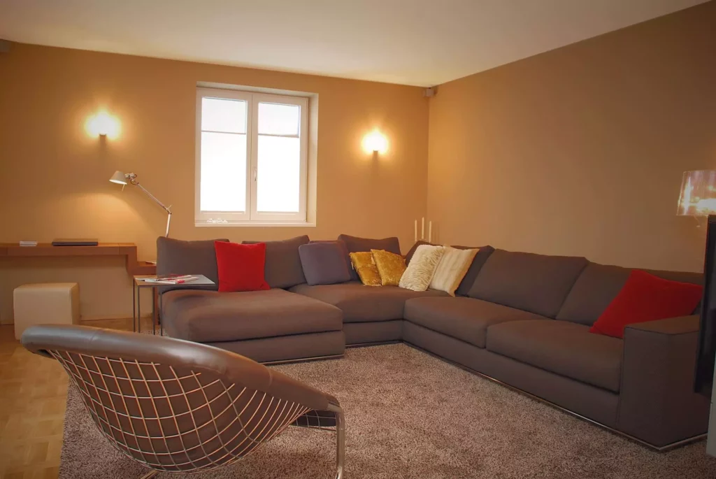 Wohnzimmer mit grauem Ecksofa, bunten Kissen, Lederstuhl mit Metallgestell, Teppich und schlichter, Referenzen