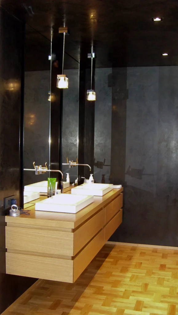 Modernes Badezimmer mit hängendem Holzwaschtisch, zwei weißen Aufsatzbecken, großem Spiegel und dunklen Wänden, Referenzen