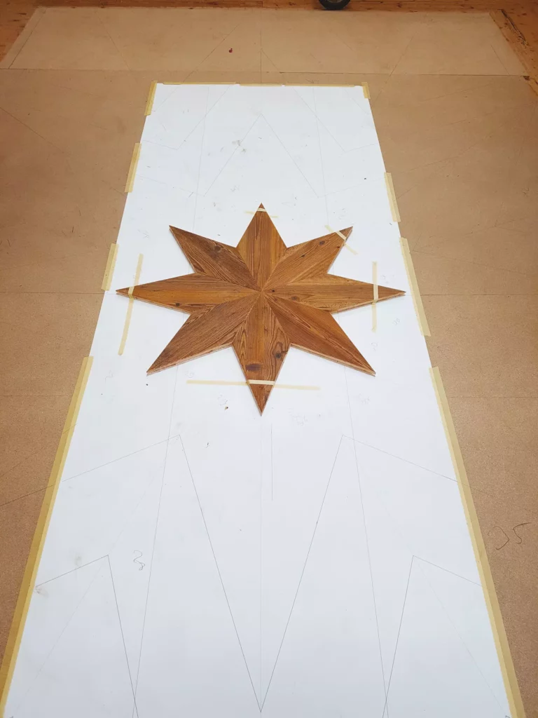 Maßgefertigte Holz-Einlegearbeit in Form eines achtzackigen Sterns auf einer Schablone in der Tischlerei für, Meisterstueck