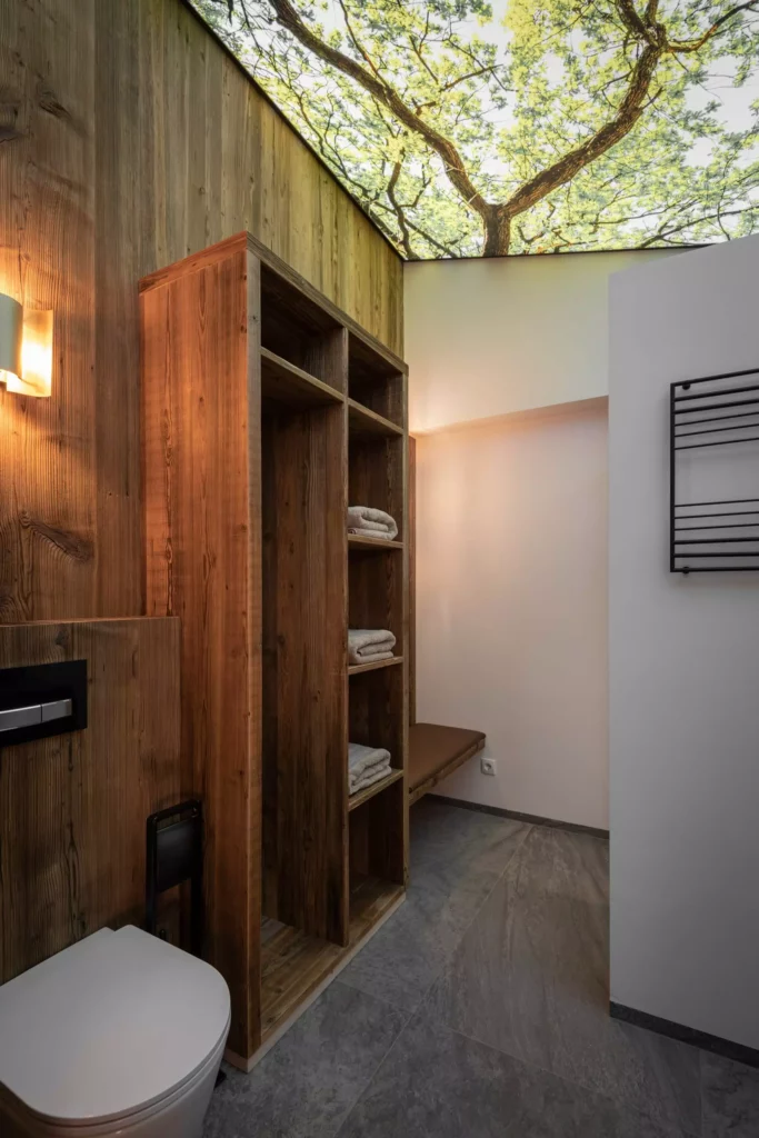 Modernes Badezimmer mit maßgefertigtem Massivholz-Regal, Sitzbank, grauem Boden und Deckenlicht mit Baum-Motiv, Minotti