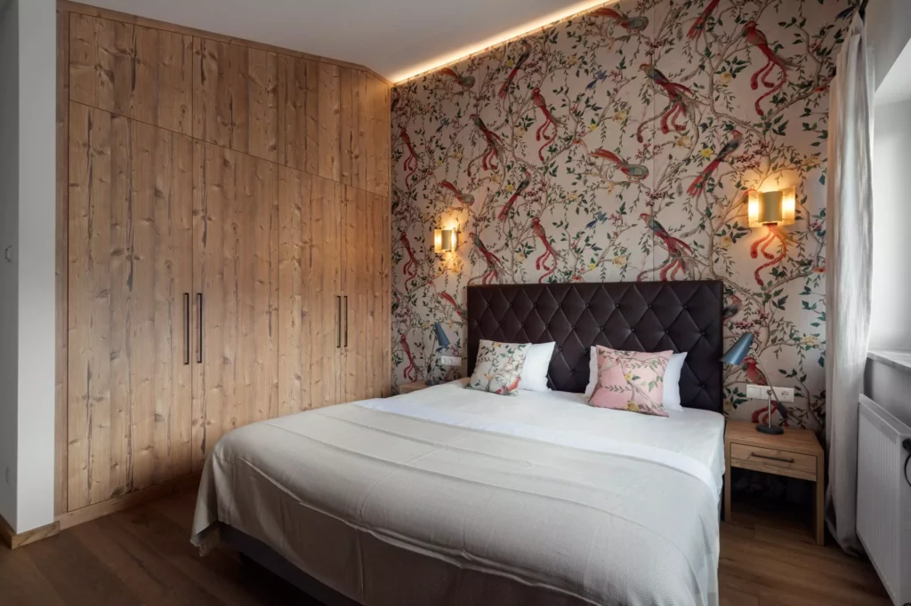 Schlafzimmer mit maßgefertigtem Massivholz-Kleiderschrank, gepolstertem Kopfteil, floral gemusterter Tapete und, Minotti