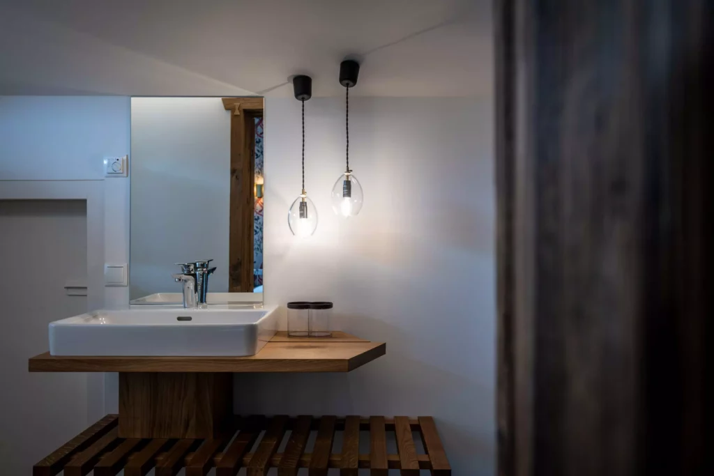 Moderner Waschtisch aus Massivholz mit weißem Aufsatzbecken, zwei hängenden Glühlampen und rechteckigem Spiegel in, Minotti