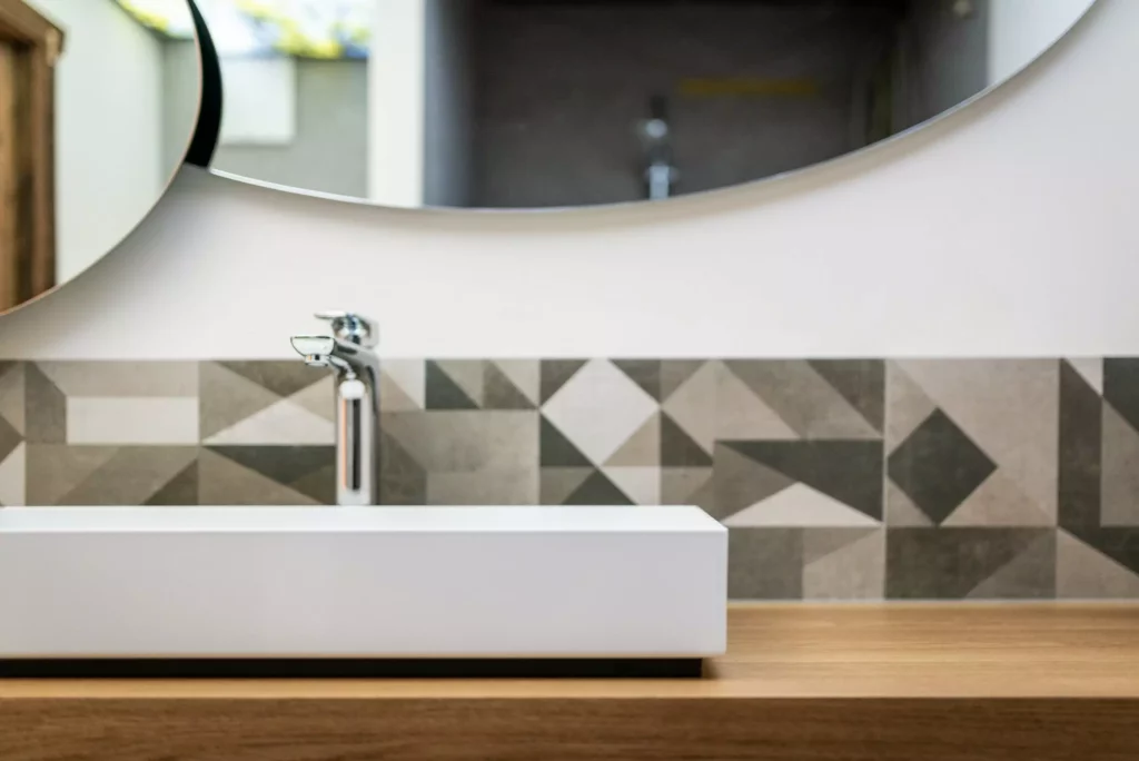 Moderner Waschtisch mit weißem Becken, Holzplatte und geometrisch gemusterten Fliesen im Badezimmer, Minotti