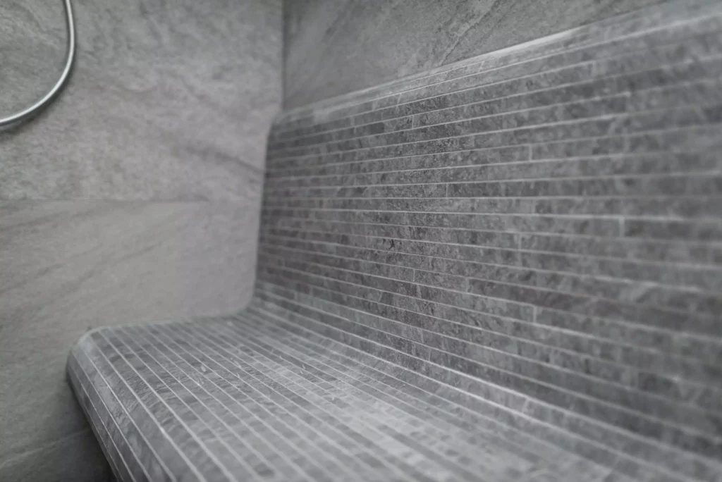 Sitzbank aus grauen Mosaikfliesen in moderner Innenarchitektur mit Wand aus großformatigen grauen Fliesen, Minotti