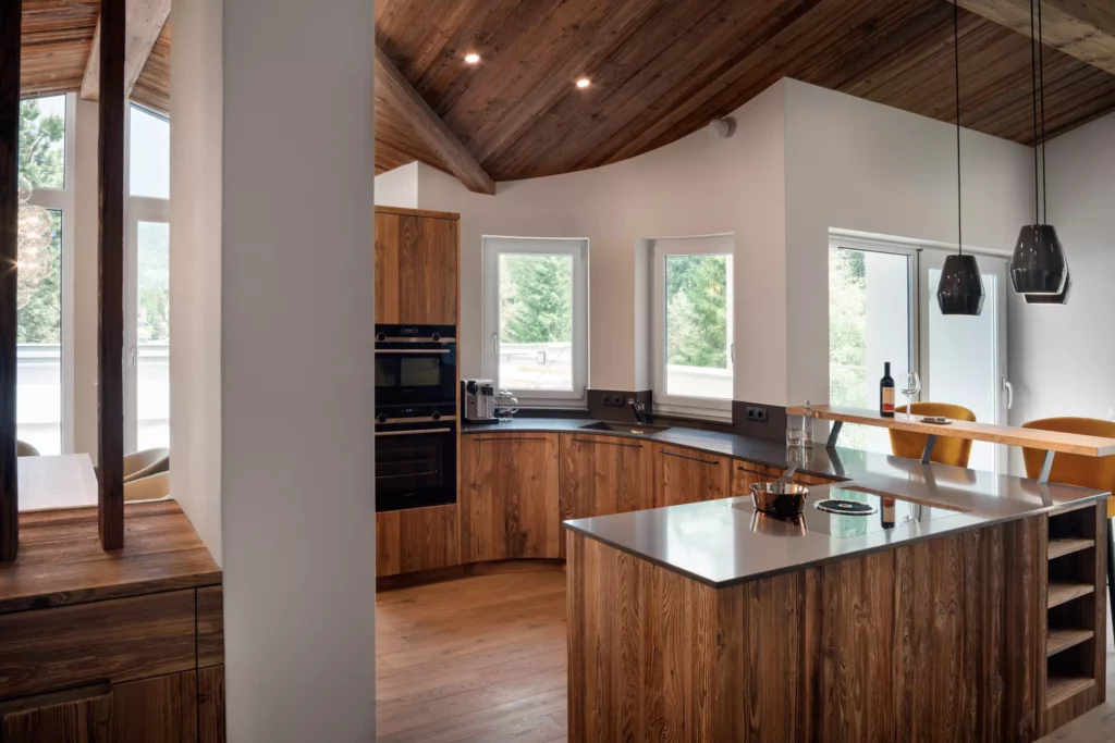 Moderne Küche mit maßgefertigten Massivholzmöbeln, Kochinsel, Einbaugeräten und großen Fenstern in einem Chalet mit, Minotti