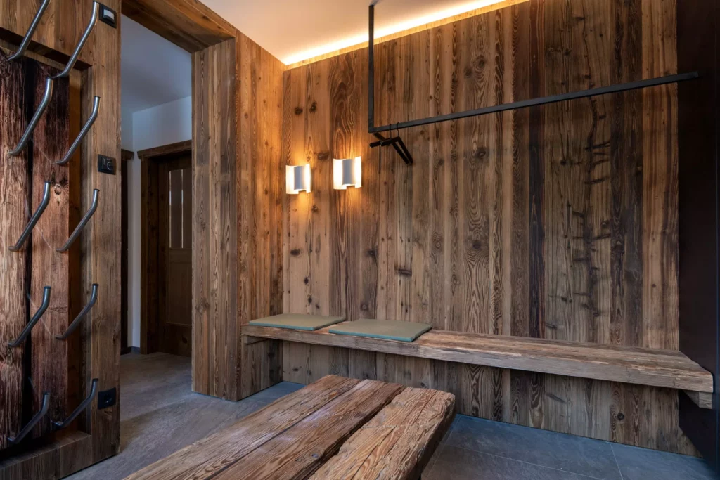 Rustikaler Eingangsbereich mit Massivholz-Wandverkleidung, Sitzbank mit Polstern, Garderobenhaken und, Minotti
