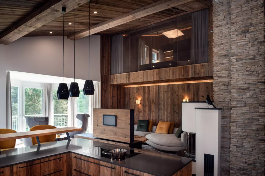 Moderne Wohnraumplanung mit Massivholz-Küche, gemütlicher Sitzecke, Kamin und großen Fenstern im Minotti Chalet in Salzburg