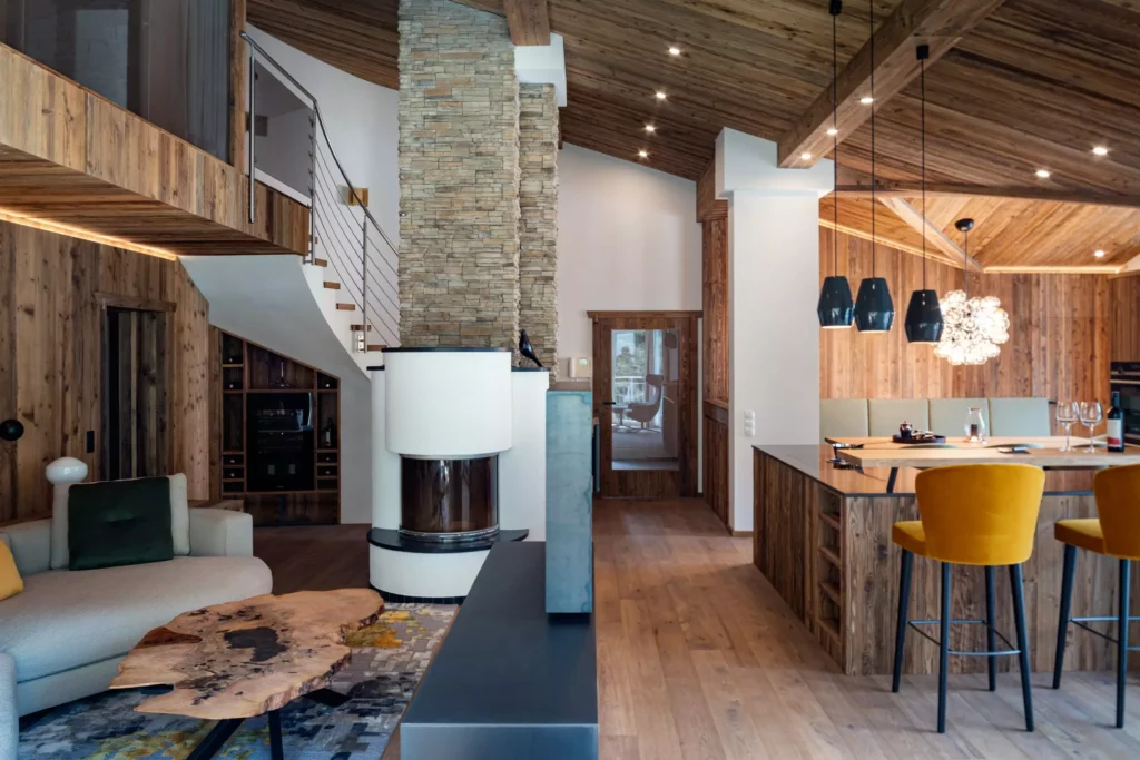 Wohnraum mit maßgefertigtem Massivholztisch, Kamin mit Natursteinverkleidung, offener Küche und gelben Barhockern im, Minotti