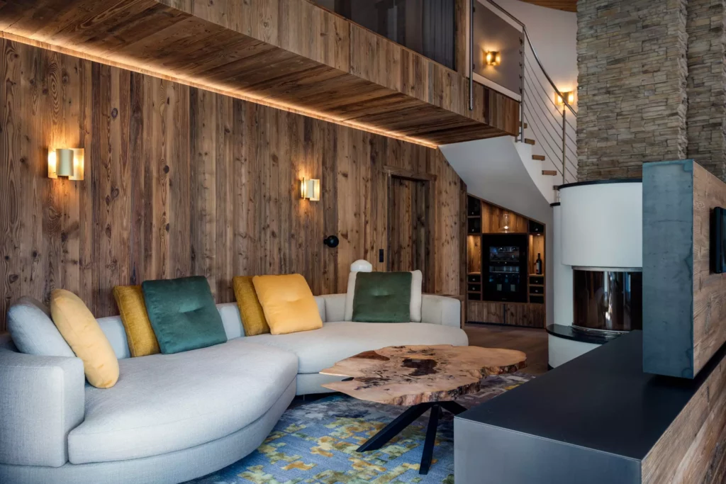 Wohnzimmer mit maßgefertigtem Massivholz-Wohnraumkonzept, Minotti Sofa, rustikaler Holzwand, Naturholz-Tisch und Kamin in