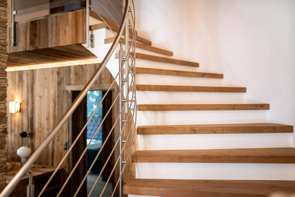 Moderne Treppe mit massiven Holzstufen und Edelstahlgeländer in einem Innenraum mit Holzverkleidung und indirekter, Minotti