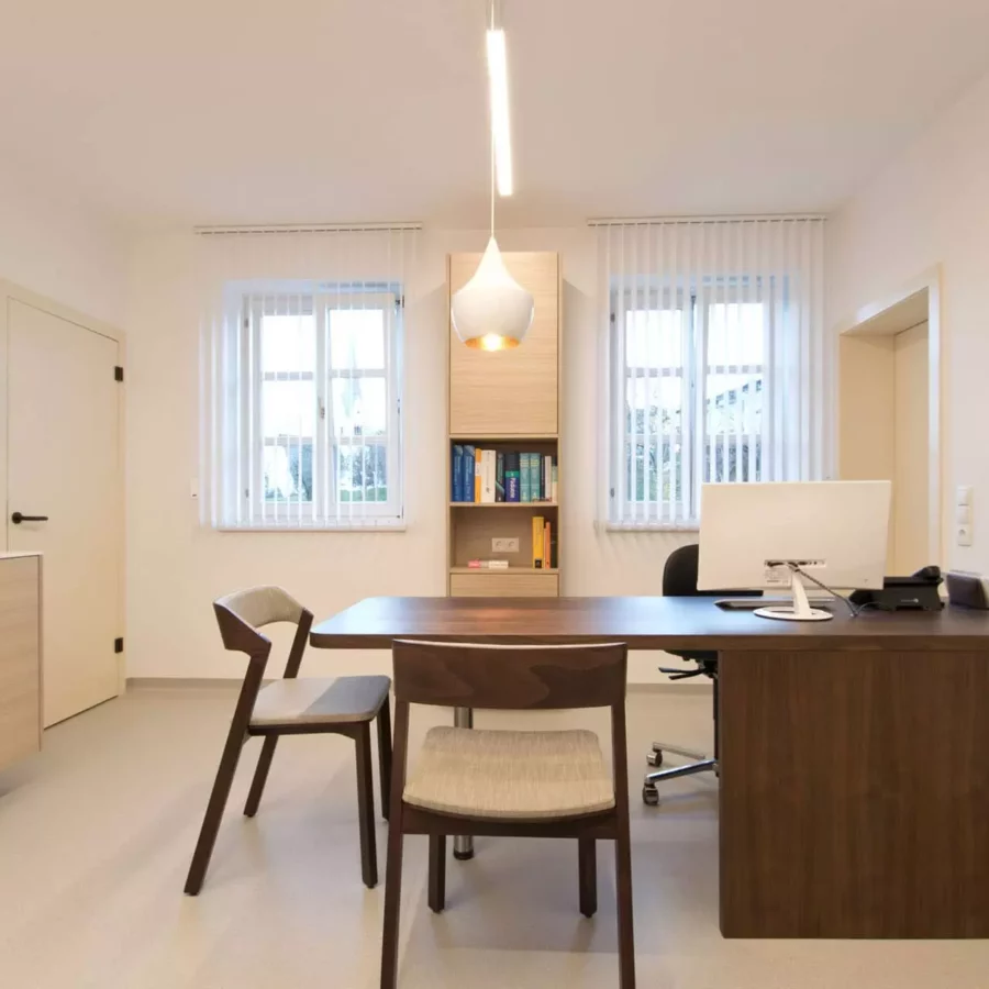 Moderner Besprechungsraum einer Arztpraxis mit maßgefertigtem Holztisch, Stühlen und heller Innenarchitektur in, Referenz