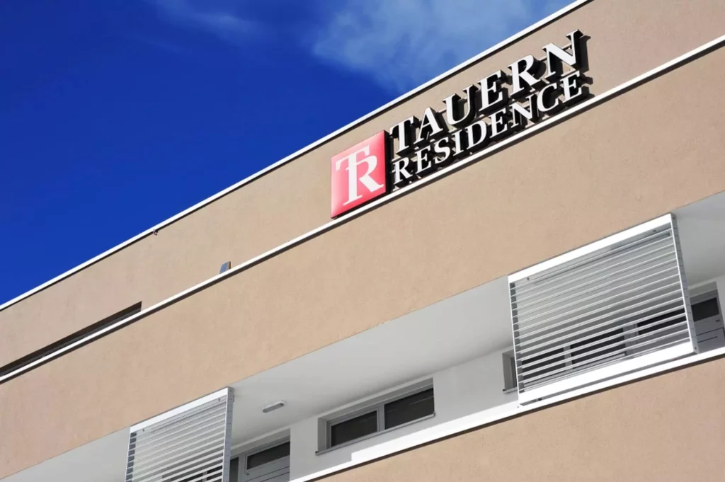 Fassade der Tauern Residence mit modernem Design und klaren Linien unter blauem Himmel in Radstadt, Referenz