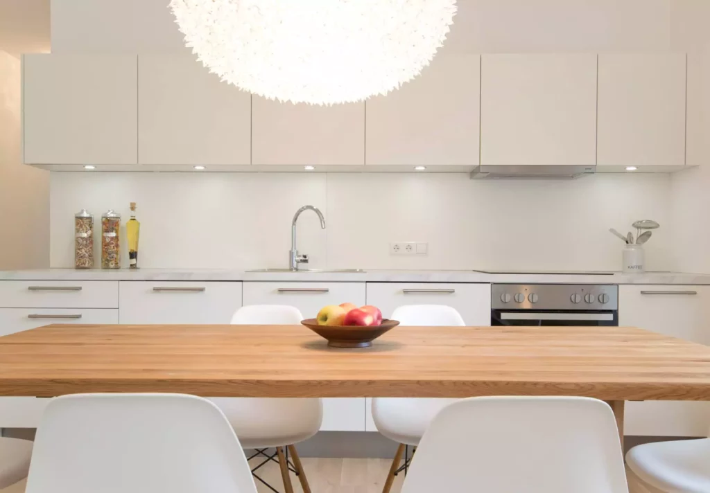 Moderne weiße Küche mit Holz-Esstisch, Designermöbeln, Vitra-Stühlen und Obstschale im Ferienwohnung-Projekt, Referenz