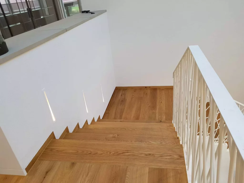 Holztreppe mit weißem Geländer und integrierten Wandlichtern in moderner Innenarchitektur einer Villa in Stuttgart, Referenz
