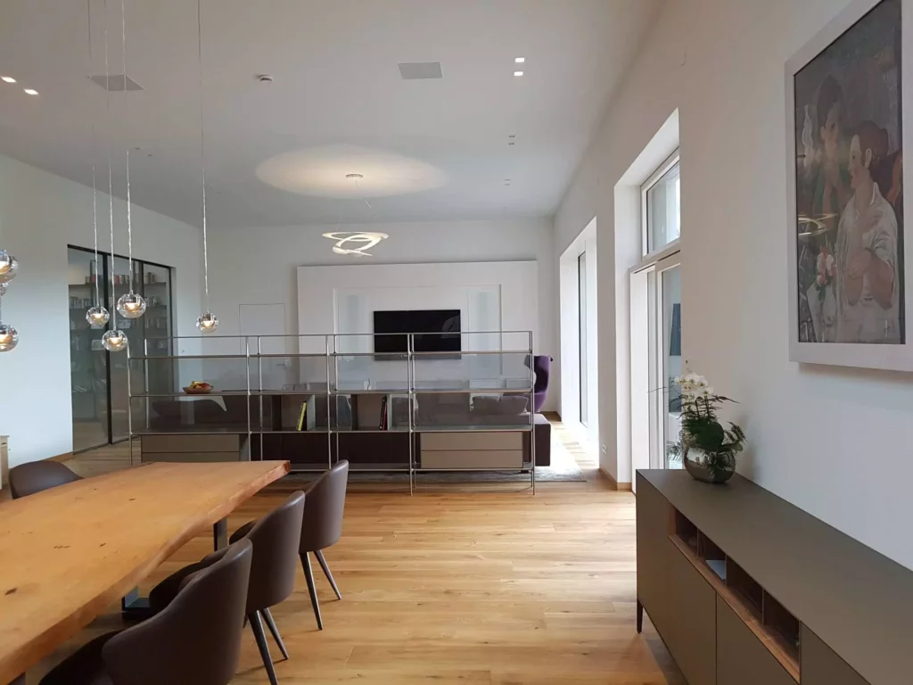 Moderner Wohnraum mit maßgefertigter Wandverkleidung, Poliform Sideboard, Rimadesio Raumteiler und Minotti Stühlen, Referenz