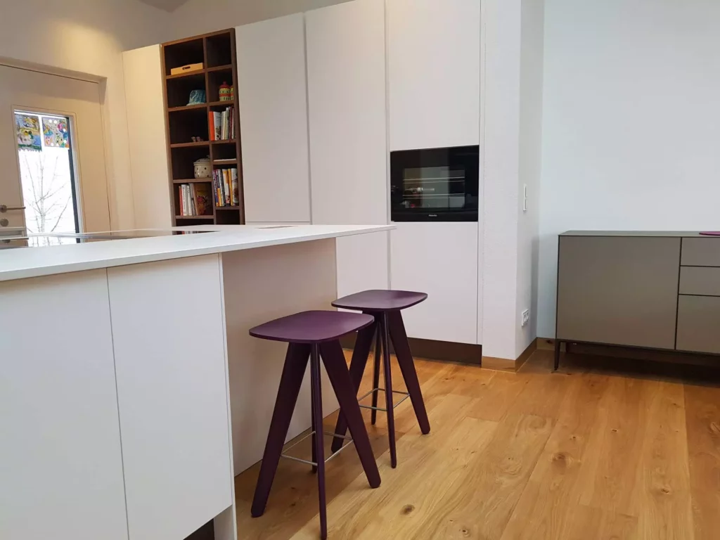 Moderne weiße Küche mit maßgefertigter Wandverkleidung, zwei violetten Barhockern und Holzboden in Villa Stuttgart, Referenz