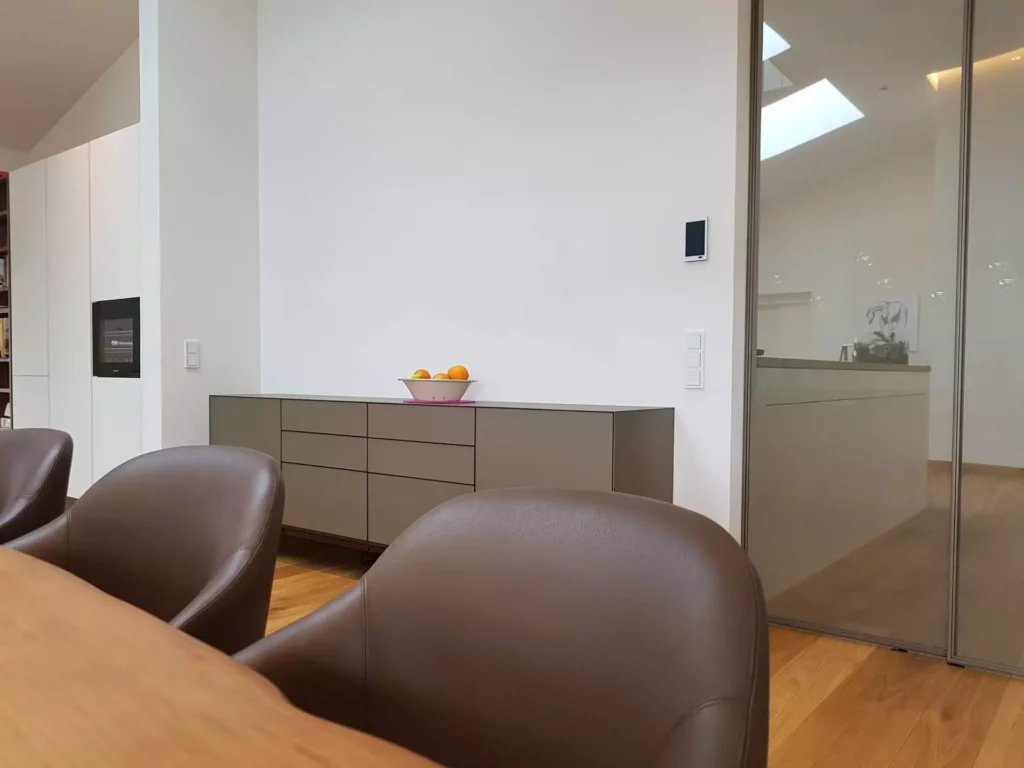 Moderner Essbereich mit braunen Lederstühlen, Sideboard und gläserner Wand in einer Villa in Stuttgart, Referenz