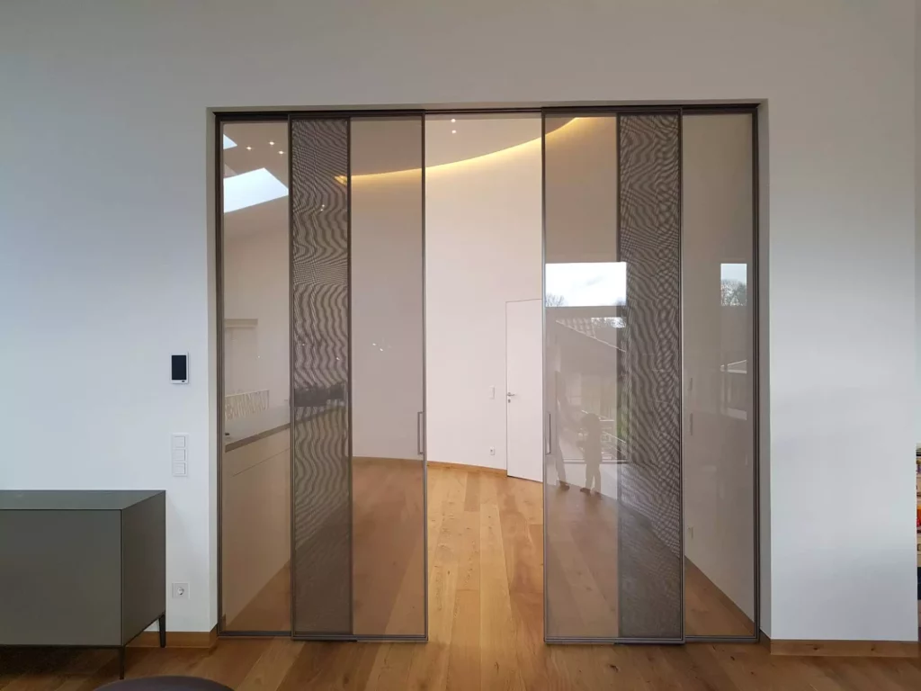 Schiebetüren mit getöntem Glas und filigranen Rahmen als Raumtrennung in moderner Villa mit Parkettboden und, Referenz