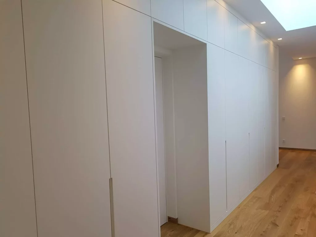 weiße maßgefertigte wandverkleidung mit integrierter tür in flur mit holzboden und deckenbeleuchtung, Referenz