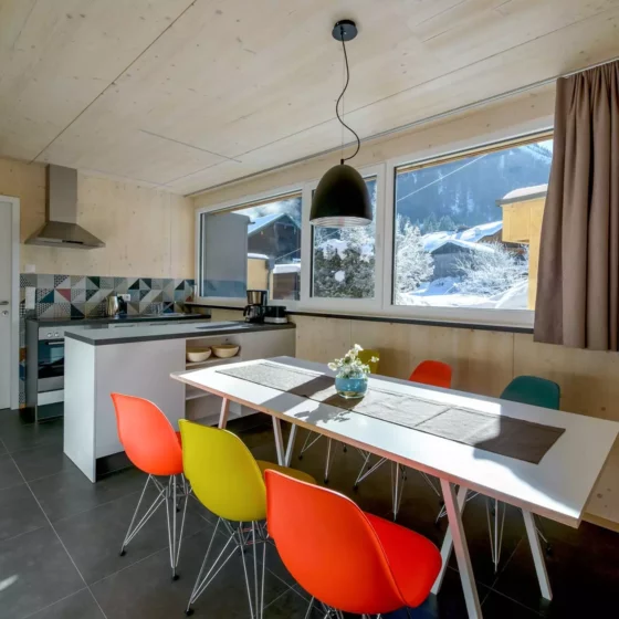 Moderne Küche mit Vitra DSR Stühlen in bunten Farben, weißem Tisch, Holzverkleidung und großem Fenster mit, Referenz