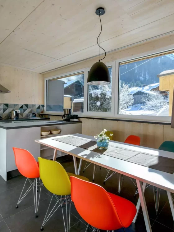 Moderne Küche mit Vitra DSR Stühlen in bunten Farben, weißem Tisch, Holzverkleidung und großem Fenster mit, Referenz