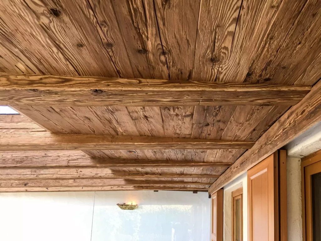 Decke aus Altholz mit sichtbaren Balken und Fenstern mit Holzläden in einem Innenraum als Beispiel für, Altholzmöbel